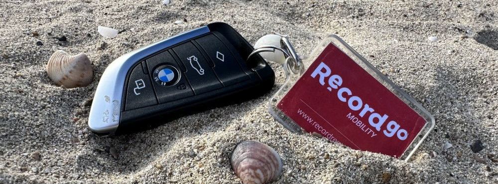 Ein Mietwagen Schlüssel liegt im Sandstrand