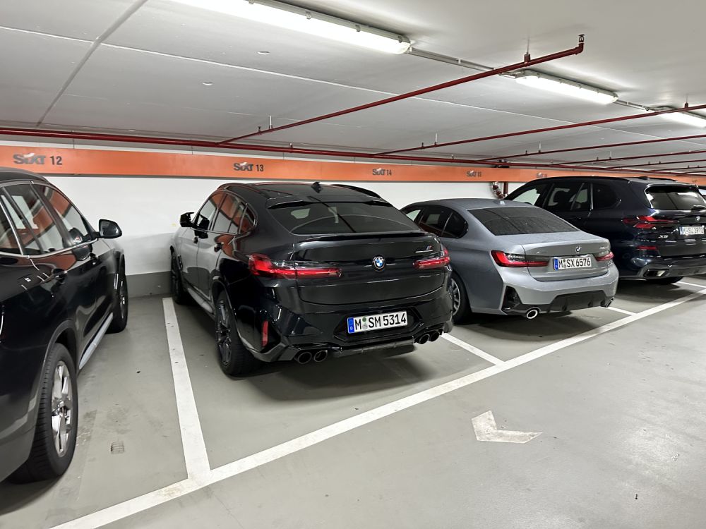 BMW X4 in Schwarz auf einem Sixt-Stellplatz in einem Parkhaus, umgeben von weiteren BMW-Modellen.