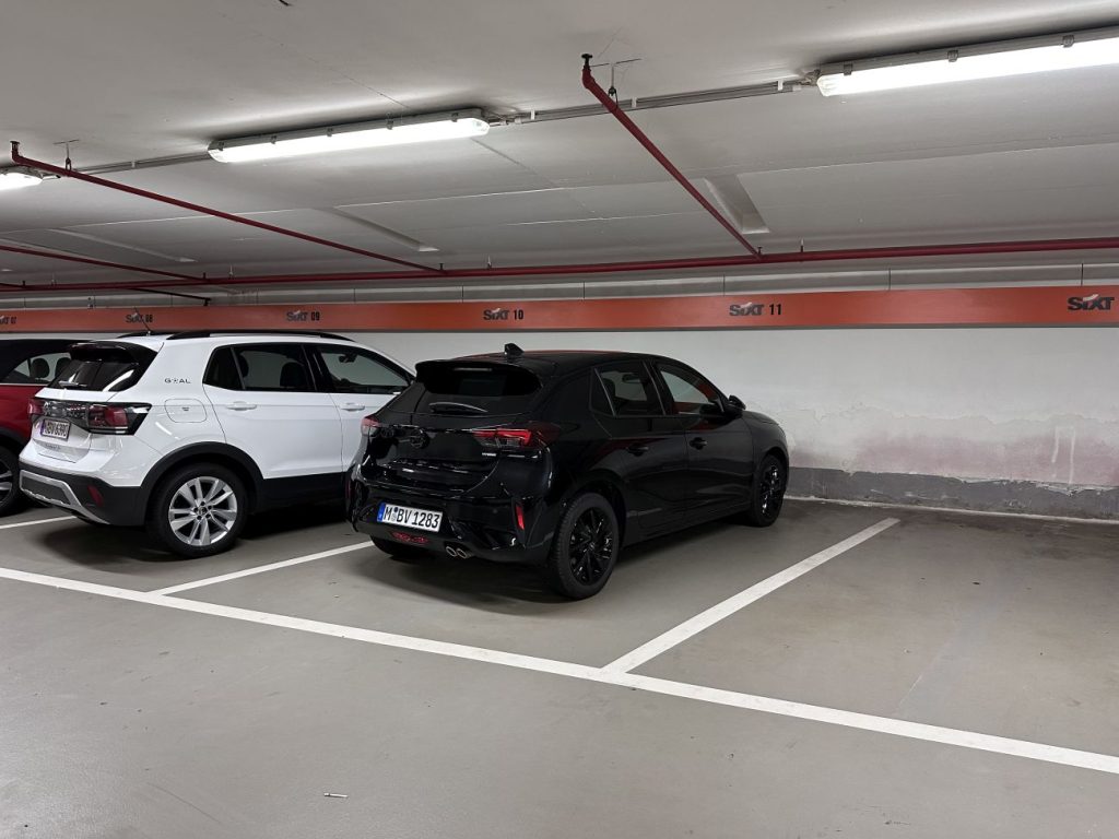 Schwarzer Opel Corsa in einer Tiefgarage auf einem Sixt-Parkplatz.