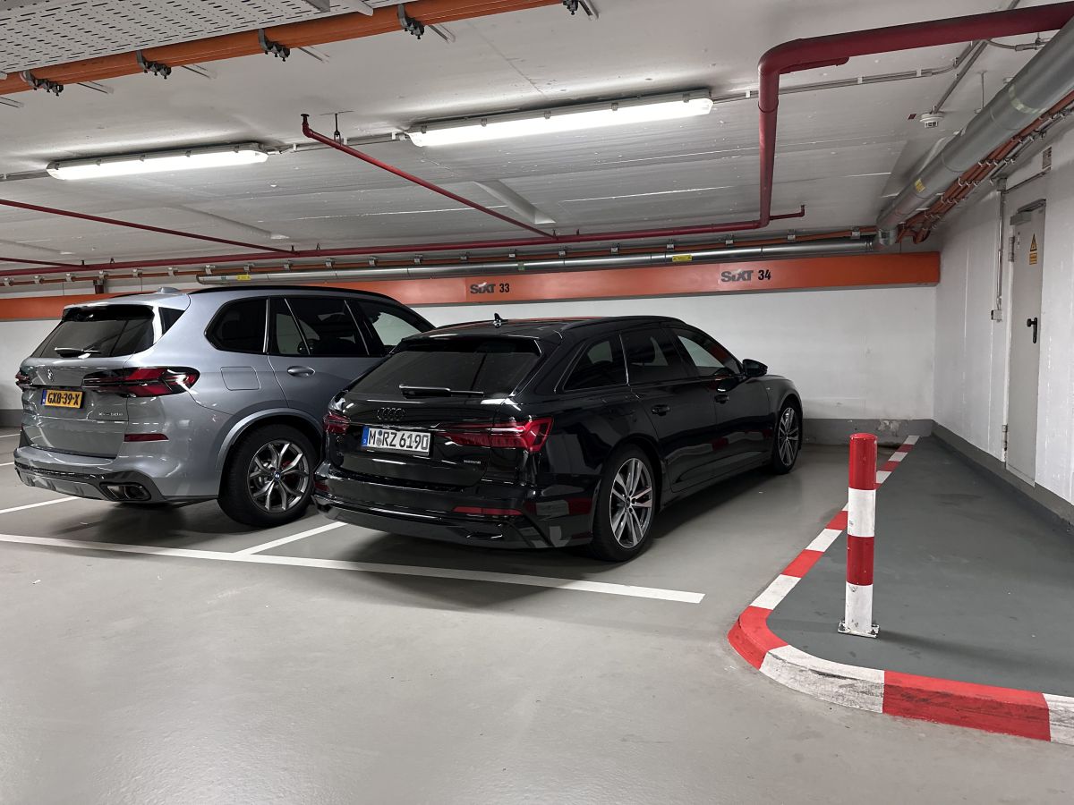 Schwarzer Sixt Audi A6 Avant parkt in einer Tiefgarage, Heckansicht mit LED-Rückleuchten und deutschem Kennzeichen.